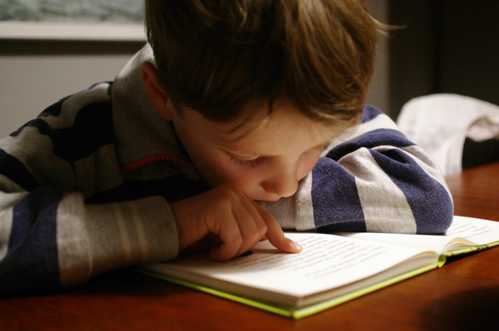 Enfant qui lit un livre à une table en bois